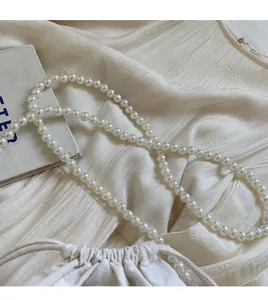 Close-up of elegant white pearl handle strap on a minimalist woven straw bucket bag