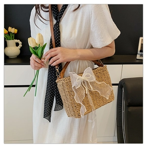 Detailed texture of straw woven bag featuring a large mesh bow and elegant pearl chain
