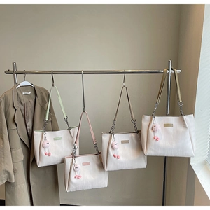 Detail of four colorful tote bags with chain straps and plush charms in chic display
