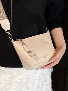 Minimalist beige dumpling crossbody bag with ethnic geometric strap and leather fringe