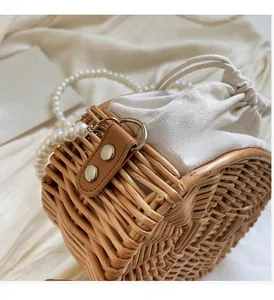 Close-up of woven rattan bucket bag with white pearl strap and gold metal hardware