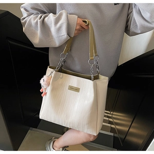 Detail of white tote bag with vertical textures, chain strap, and cute plush charm