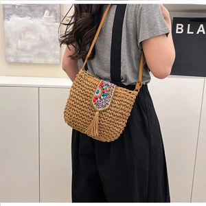 Detail of straw crossbody bag featuring ethnic beadwork and long tassels on the flap