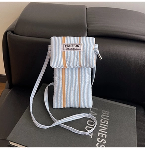 Detailed macro view of striped fabric phone bag with adjustable strap on a dark background