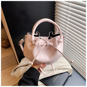 Detail view of pink wax leather bucket bag with bow drawstring and top handle