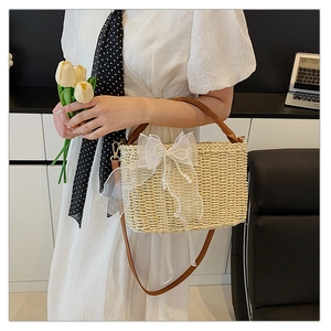 Detail of woven straw bag with white mesh bow, pearl accents and brown leather handle