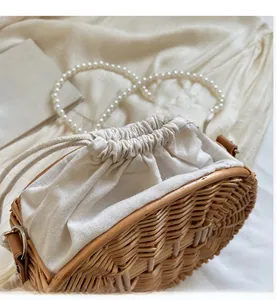 Detail of hand-woven straw bag with beige drawstring lining and pearl shoulder strap