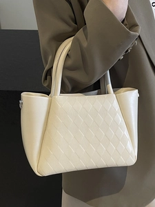 Elegant cream quilted bucket bag with top handles shown with a dark professional blazer