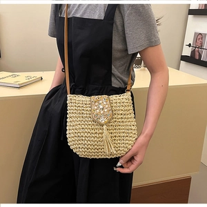Detail of straw woven crossbody bag featuring colorful sequins and long fringe tassels