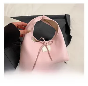 Close-up of pink bow handbag with silver metal chain strap and white brand tag