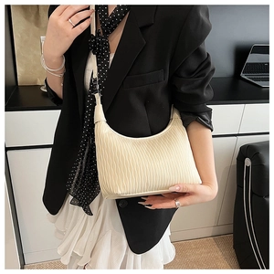 Close-up of beige pleated dumpling bag with vertical wave texture on a female model