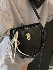 Sac seau minimaliste en cuir noir avec fermoir rotatif en métal et pendentif de tennis