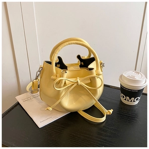 Close-up of light yellow oil wax leather bucket bag with decorative bow and shoulder strap