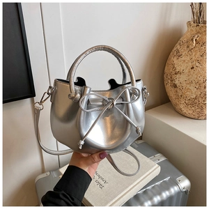 Metallic silver bucket bag with bow drawstring handle and long shoulder strap detail