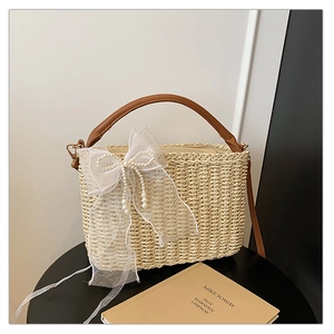 Close-up of woven straw bag with white lace bow and pearl beads for beach vacation style
