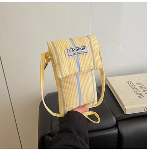 Detail of yellow and white striped fabric crossbody bag with blue vertical accent strap