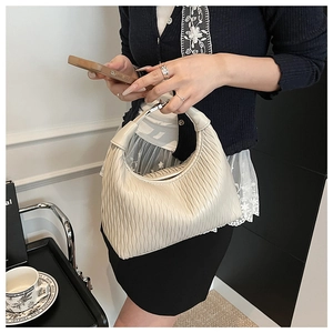Close-up of beige dumpling bag with unique pleated texture and smooth vegan leather handle
