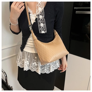 Close-up of pleated apricot crescent bag featuring vertical texture and adjustable strap