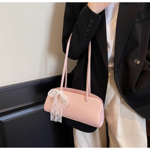 Rosa Baguette-Tasche mit weißer Spitzenschleife an einem Modell in der Seitenansicht