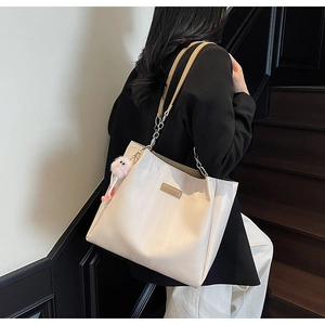 Off-white tote bag detail with chain strap and pink plush ball charm on a model