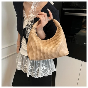 Detail of beige hobo bag with unique pleated texture and integrated wide handle design