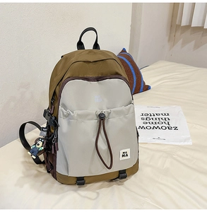Dettaglio dello zaino patchwork marrone e beige con logo Nana e ciondolo a cane