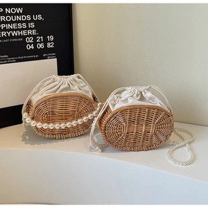 Detail view of woven straw bag featuring white drawstring liner and large faux pearl strap