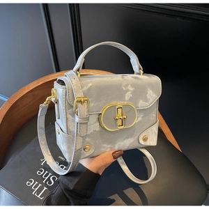 Detail of grey marble leather box bag with golden oval lock and adjustable shoulder strap