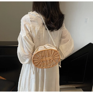 Detail of straw crossbody bag with white pearl strap and drawstring inner lining