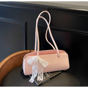Detailaufnahme einer rosa Baguette-Tasche mit Doppelriemen und weißem Spitzenanhänger
