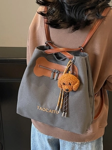 Mochila chic de lona gris oscuro con ribetes de cuero y colgante de oso de peluche