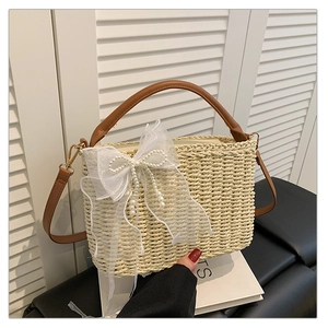 Detail of hand-woven straw bag featuring pearl lace bow and brown leather handle