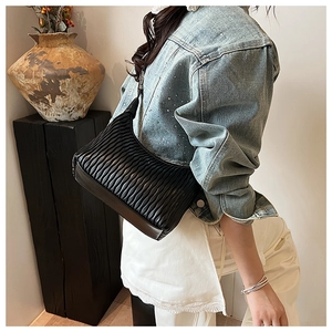 Detail of black pleated crossbody bag with a matte texture on a fashion model