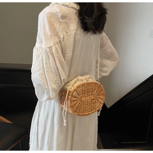 Detail of hand-woven straw bag featuring pearl strap and secure drawstring closure