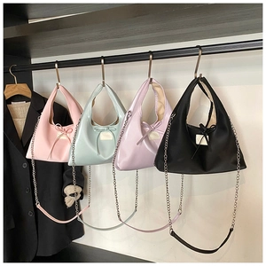 Detail view of four pastel half-moon handbags with bows and silver chain straps