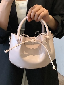 Chic light pink oil wax leather bucket bag with a bow drawstring and rounded handle