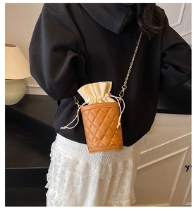 Detail of a brown quilted bucket bag with golden chain strap and drawstring closure