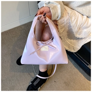 Detail of light purple dumpling bag with ribbon bow and silver chain strap for women