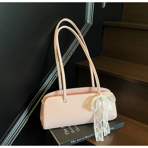 Detailansicht der rosa Baguette-Tasche aus Leder mit großer weißer floraler Spitzenschleife