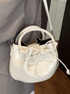Minimalist beige oil wax leather bucket bag with top handle and drawstring detail