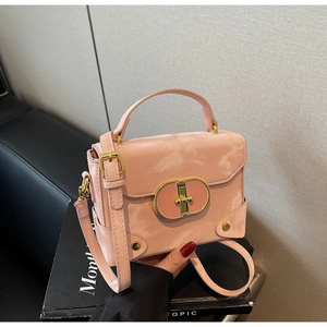 Detail view of pink glossy handbag with gold oval lock and elegant metal rivet accents