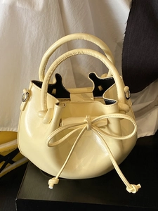 Minimalist cream oil wax leather bucket bag with a bow tie detail and round handles