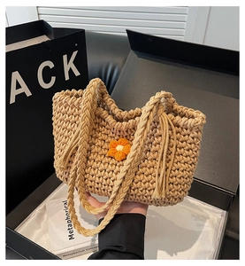 Close-up of knit tote bag featuring 3D crochet flowers and braided tassel handles