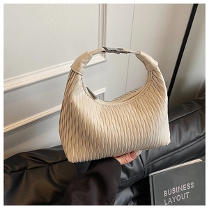 Close-up of beige pleated dumpling bag featuring vertical texture and silver metal hardware