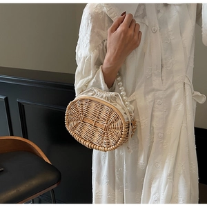 Detailed texture of straw woven handbag featuring elegant pearl bead handle and drawstring