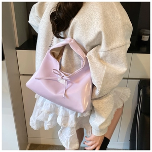 Close-up of light purple dumpling bag with glossy PU leather, bow detail and metal chain