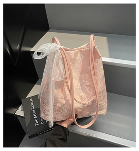 Dettaglio della borsa tote in pizzo rosa con ricamo a farfalla 3D e ciondolo a fiocco