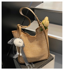 Détail du sac cabas en paille tissée main avec garniture en cuir brun et breloque