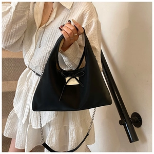 Close-up of black nylon handbag featuring a decorative bow and elegant silver chain strap