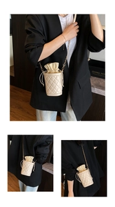 Detailed view of cream quilted bucket bag featuring drawstring closure and gold chain strap
